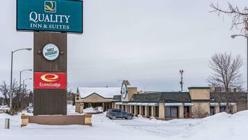 A Quality Inn & Suites sign, a Family Restaurant sign, and an EconoLodge sign in a snowy parking lot.