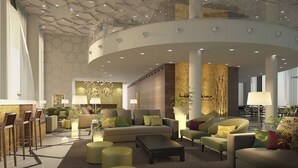 Eine geräumige Lobby mit hoher Decke, moderner Möblierung und einer zentralen Sitzecke.