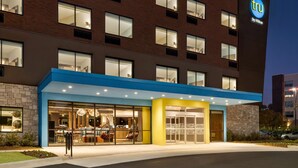 A hotel with a modern design, featuring a prominent 'tru by Hilton' sign, large windows, and a well-lit entrance.