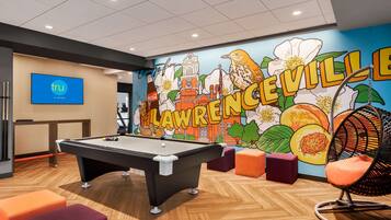Relax in the hotel's vibrant recreational room, featuring a pool table, colorful seating, and a large mural showcasing the local theme.