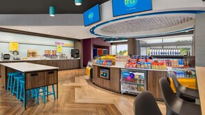 A modern hotel lobby with a bar area, seating, and a refrigerated display.