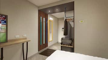 Ein Hotelzimmer mit einem Bett, einem kleinen Tisch, einem Fernseher und einem Kleiderständer mit Kleidung.