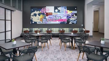 Un interior moderno con un mural grande en la pared, una zona de estar y mesas.