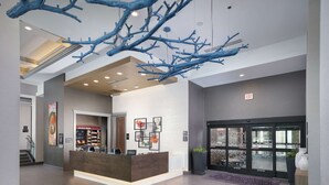A modern hotel lobby with a reception desk, a large blue abstract sculpture, and a glass door entrance. - Hampton Inn & Suites Atlanta Decatur/Emory (Decatur)