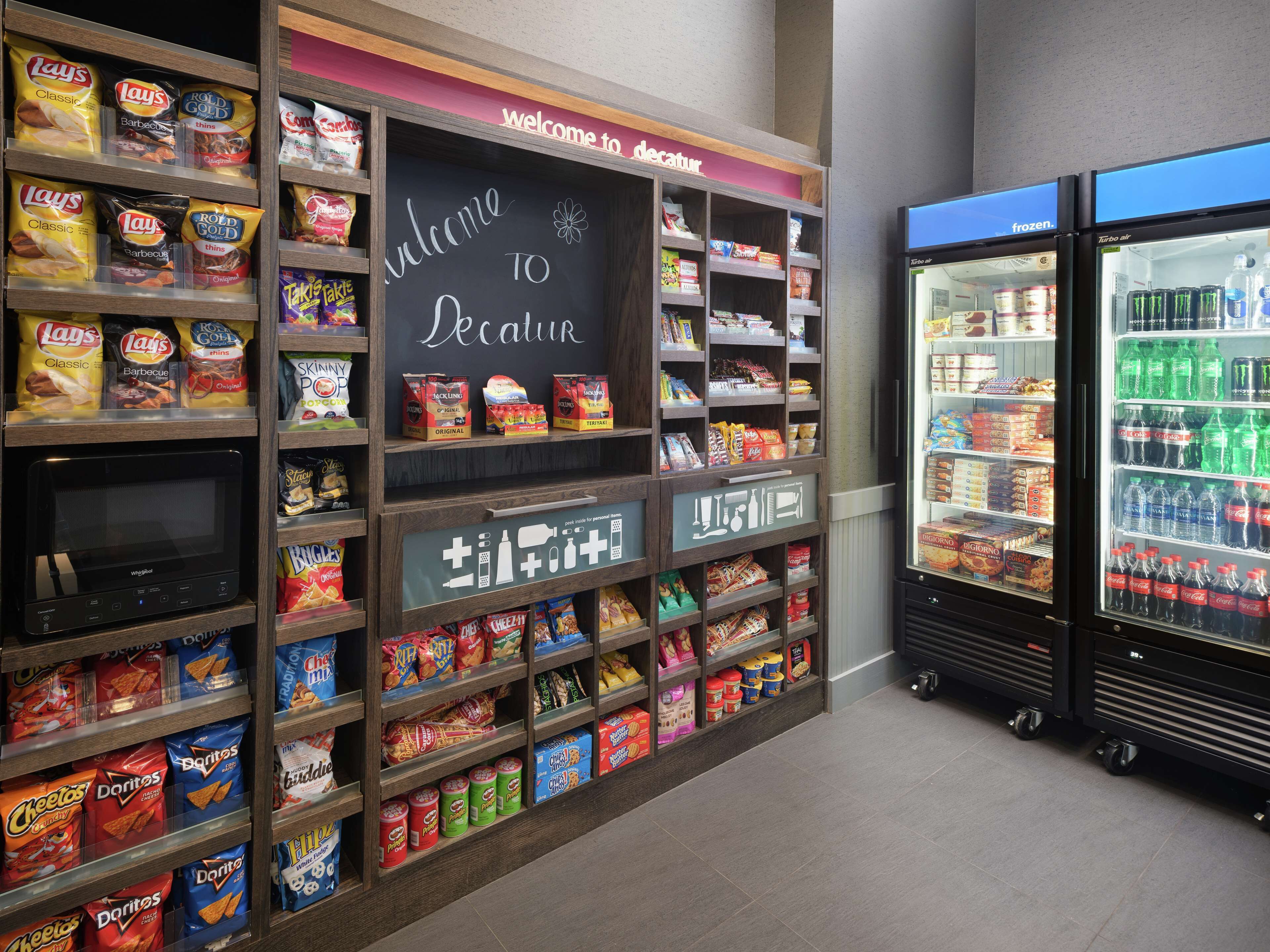 A snack display with Lay's and Doritos, a chalkboard sign, and a refrigerated drink cooler.