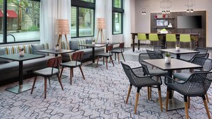 A modern hotel lobby with a seating area, tables, and a bar. - Hampton Inn & Suites Atlanta Decatur/Emory (Decatur)