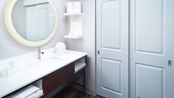 A modern bathroom with a round mirror, white sink, and two white doors.
