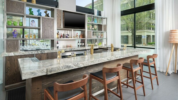 A modern kitchen with a marble countertop, wooden bar stools, and a large window offering a view of the outdoors. - Hampton Inn & Suites Atlanta Decatur/Emory (Decatur)