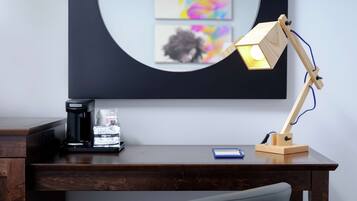 A wooden desk with a coffee maker, a smartphone, and a wooden desk lamp.