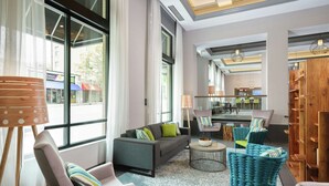 A modern hotel lobby with a grey sofa, teal armchairs, and a coffee table. - Hampton Inn & Suites Atlanta Decatur/Emory (Decatur)