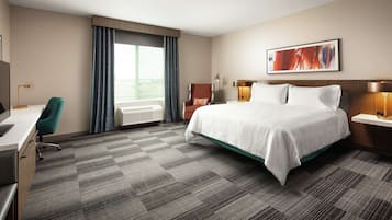 A hotel room with a large bed, a desk, a chair, and a window with curtains.