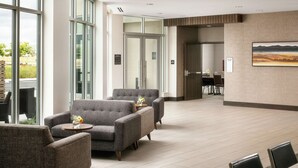 Un hall d’entrée spacieux, doté de meubles modernes, de grandes fenêtres et offrant une vue sur l’extérieur.