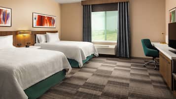 A hotel room with two beds, a desk with a chair, a TV, and a large window with curtains.
