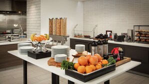 Un buffet avec des assiettes, des bols et une variété de fruits et de boissons.