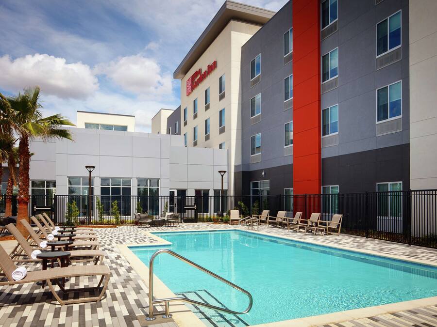 A hotel pool area with lounge chairs and a clear blue pool.