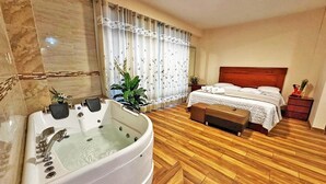 Ein Hotelzimmer mit einer großen Badewanne, einem Bett mit Holz Kopfteil und Holzboden.