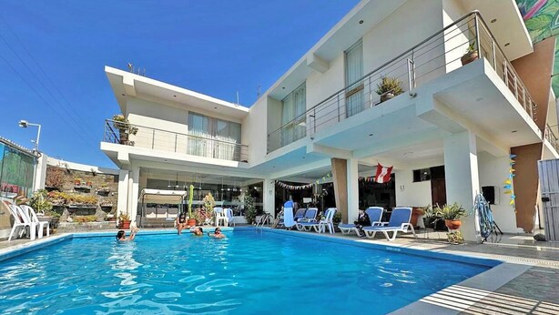 Ein modernes Hotel mit Pool, Sitzgelegenheiten im Freien und einem überdachten Bereich mit Pflanzen.