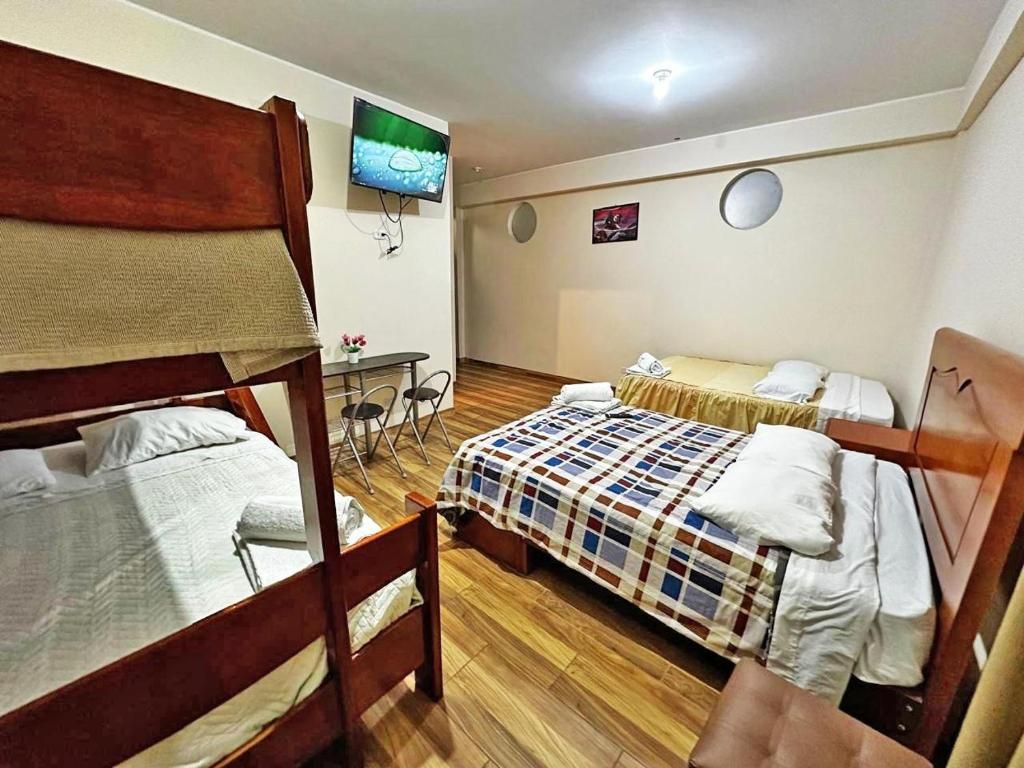 Una habitación con dos camas, televisión, una mesita y una silla.