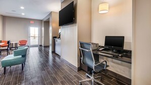 A hotel lobby with a reception desk, a TV mounted on the wall, a seating area with chairs, and a computer desk with a monitor and keyboard. - Sleep Inn & Suites Yukon Oklahoma City (Yukon)