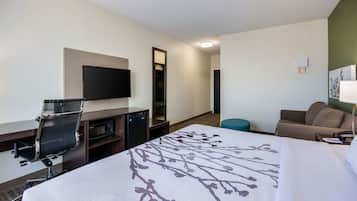 A hotel room with a bed, desk, chair, television, and a mirror.