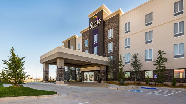 A Sleep Inn & Suites building with a modern design, featuring a covered entrance and a parking lot with handicapped parking. - Sleep Inn & Suites Yukon Oklahoma City (Yukon)