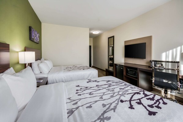 A hotel room with two beds, a TV, a desk, and a mirror.