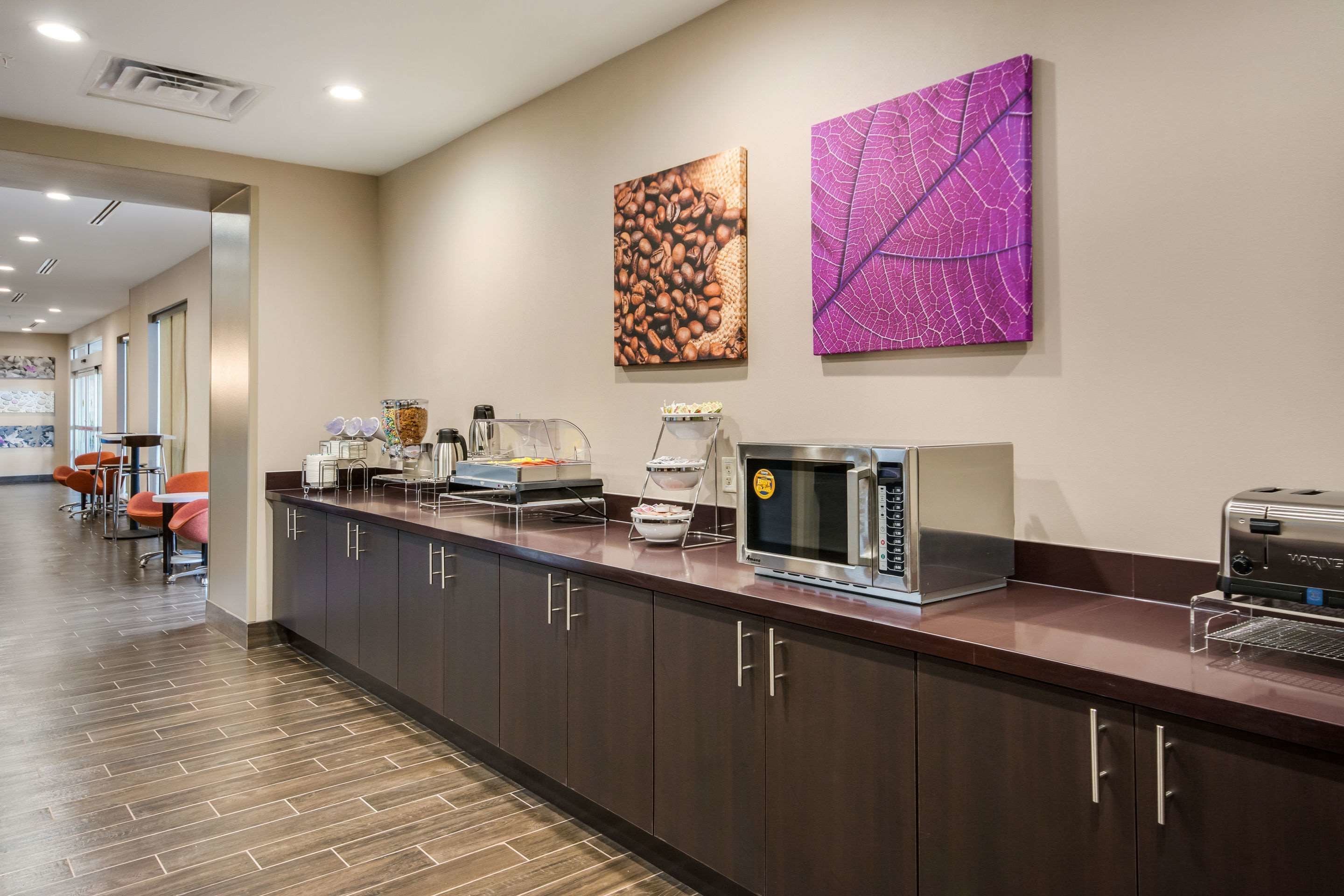 A modern kitchen area with a long counter, coffee machines, and a microwave.