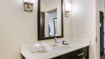 A bathroom with a white sink, dark cabinets, a large mirror, and a towel on the counter.