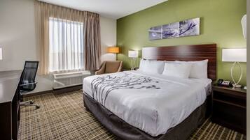 A hotel room with a large bed, a desk, a chair, a lamp, and a window with curtains.