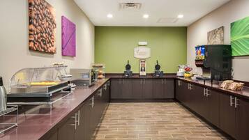 Una mesa de buffet con exhibición de café, estación de bebidas y una barra con diferentes alimentos.