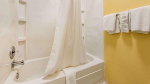 Un baño con bañera, cortina de ducha y un toallero con toallas.