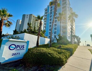 Schild für das Opus Condominium 2071, im Hintergrund ein modernes Gebäude.