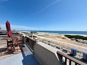 A balcony with a view of the beach and ocean.