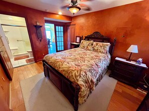 A bedroom with a wooden bed, a nightstand, a dresser, and a door leading to a bathroom.