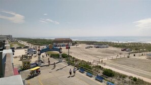 A coastal area with a paved walkway, a blue archway, and a beach in the background.
