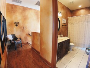A bathroom with a wooden floor, a sink, a toilet, and a shower curtain.