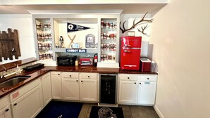 A kitchen with white cabinets, a red refrigerator, a microwave, and a toaster. There are shelves with various items and a Cowboys-themed rug. - Hatteras Hideaway - Perfect for wanting to enjoy all that Columbia has to offer. (Columbia)