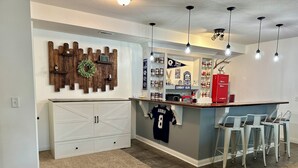 A kitchen with a bar area, white cabinets, a jersey hanging, and a red refrigerator. - Hatteras Hideaway - Perfect for wanting to enjoy all that Columbia has to offer. (Columbia)
