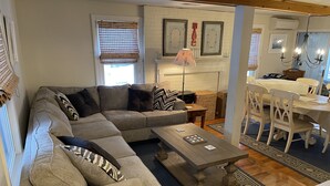Ein Wohnzimmer mit einer Eckcouch, einem Couchtisch, einem Kamin und einem Essbereich mit Tisch und Stühlen.