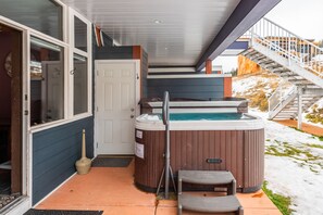 Relax in the hot tub on the covered porch, surrounded by a peaceful outdoor space.