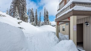 Ein mit Schnee bedecktes Gebäude mit einem Schild für Lade- und Ladezone, umgeben von schneebedeckten Bäumen.