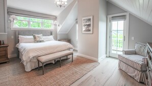 A bedroom with a large bed, a bench, a chair, a chandelier, and a picture on the wall. - 5 star, grand 8 BR estate, large yard, pool, pond, walk to town & beach (Nantucket)