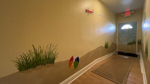 A hallway with a wall mural, a welcome sign, and an exit sign.