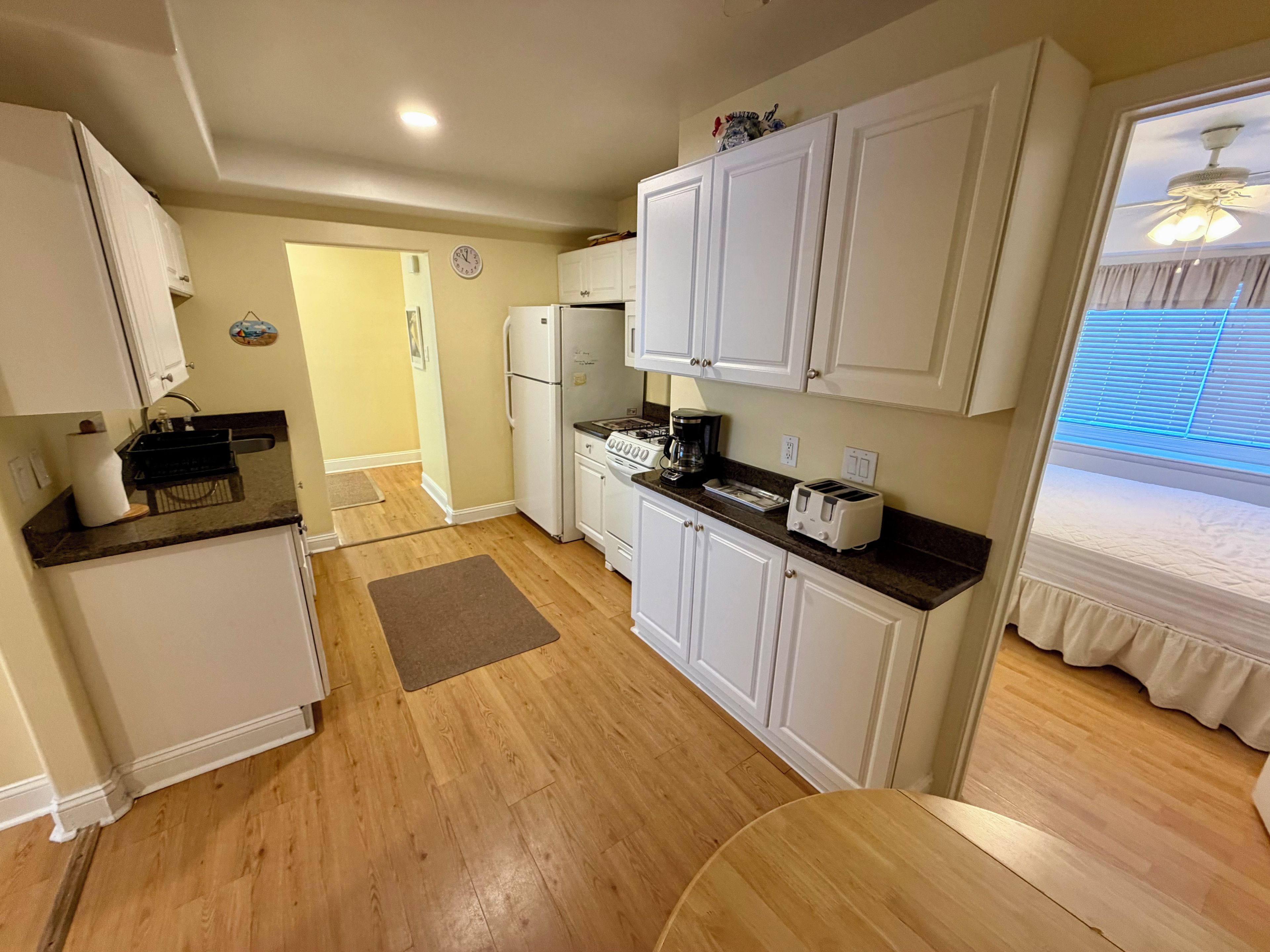 A compact kitchen with white cabinets, a refrigerator, a stove, and a toaster.