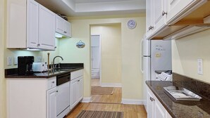 A kitchen with white cabinets, a coffee maker, a sink, and a refrigerator.