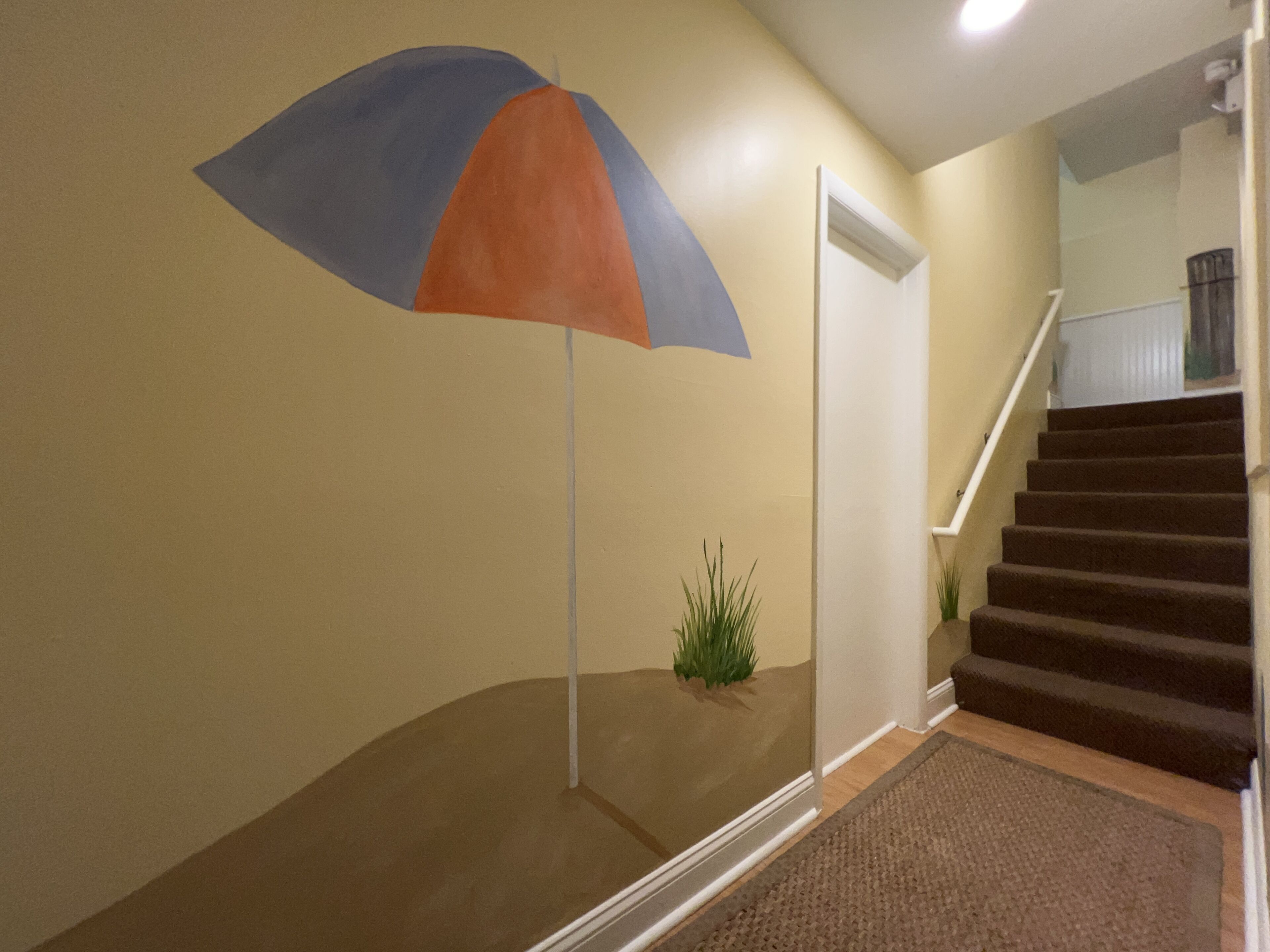 A staircase with a carpeted landing and a wall-mounted umbrella.