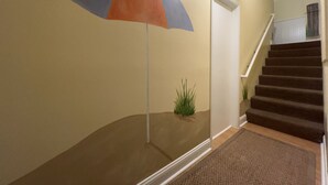 A staircase with a carpeted landing and a wall-mounted umbrella.