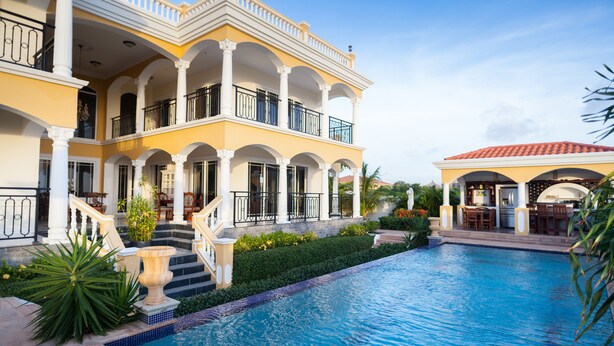 Une grande maison à deux étages, avec une piscine en premier plan.