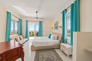 A bedroom with a bed, a sofa, a desk, and a balcony with curtains. - Villa Indijo
Luxury Sea-View Villa with Private Pool • Walk to Jan Thiel Beach (Willemstad)
