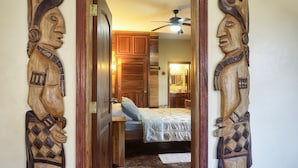 Een slaapkamer met een houten deur, een bed met een wit laken en een plafondventilator.